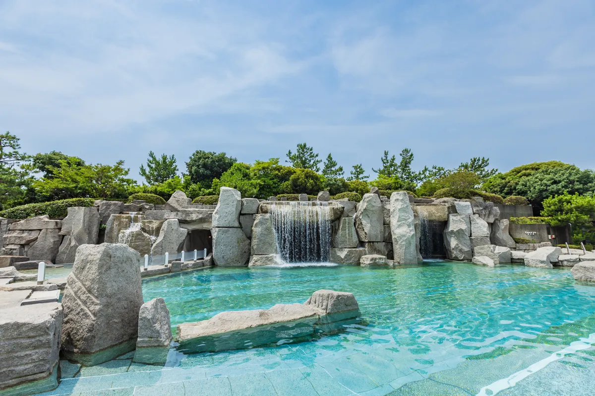 岩場から滝が流れ落ちる、広々とした開放感あふれるガーデンプールの全景